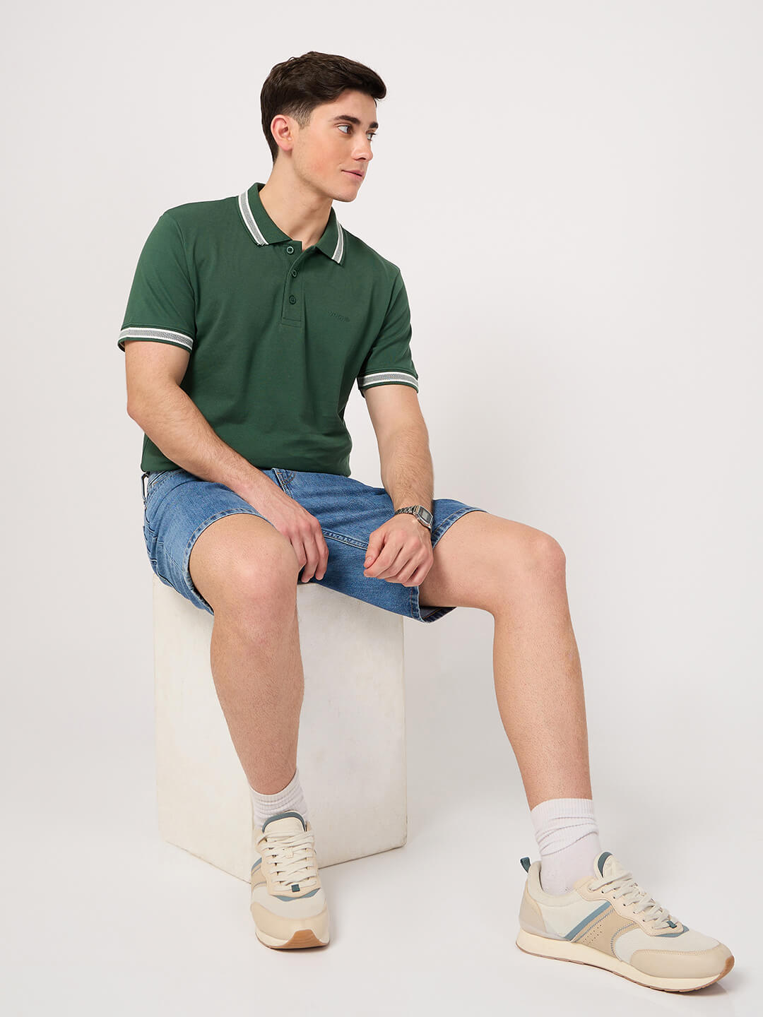 A man wearing a green polo shirt with shorts