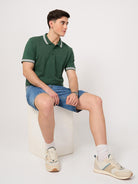 A man wearing a green polo shirt with shorts