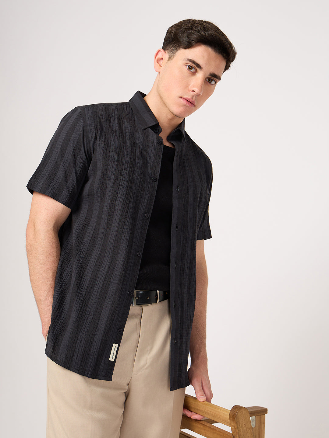 A man wearing a striped half sleeve shirt with beige pant.