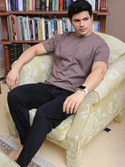Man wearing a brown crew neck cotton t-shirt and black pant sitting on a rest chair