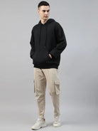 Person wearing a black hoodie and beige cargo pants on a gray background