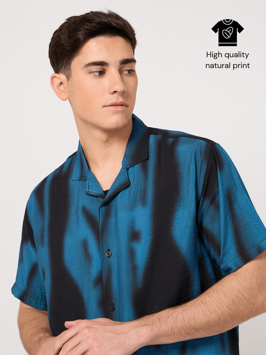 Man wearing a blue satin shirt with a plain background