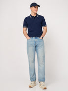 man wearing a navy blue polo shirt with jacquard collar and jeans