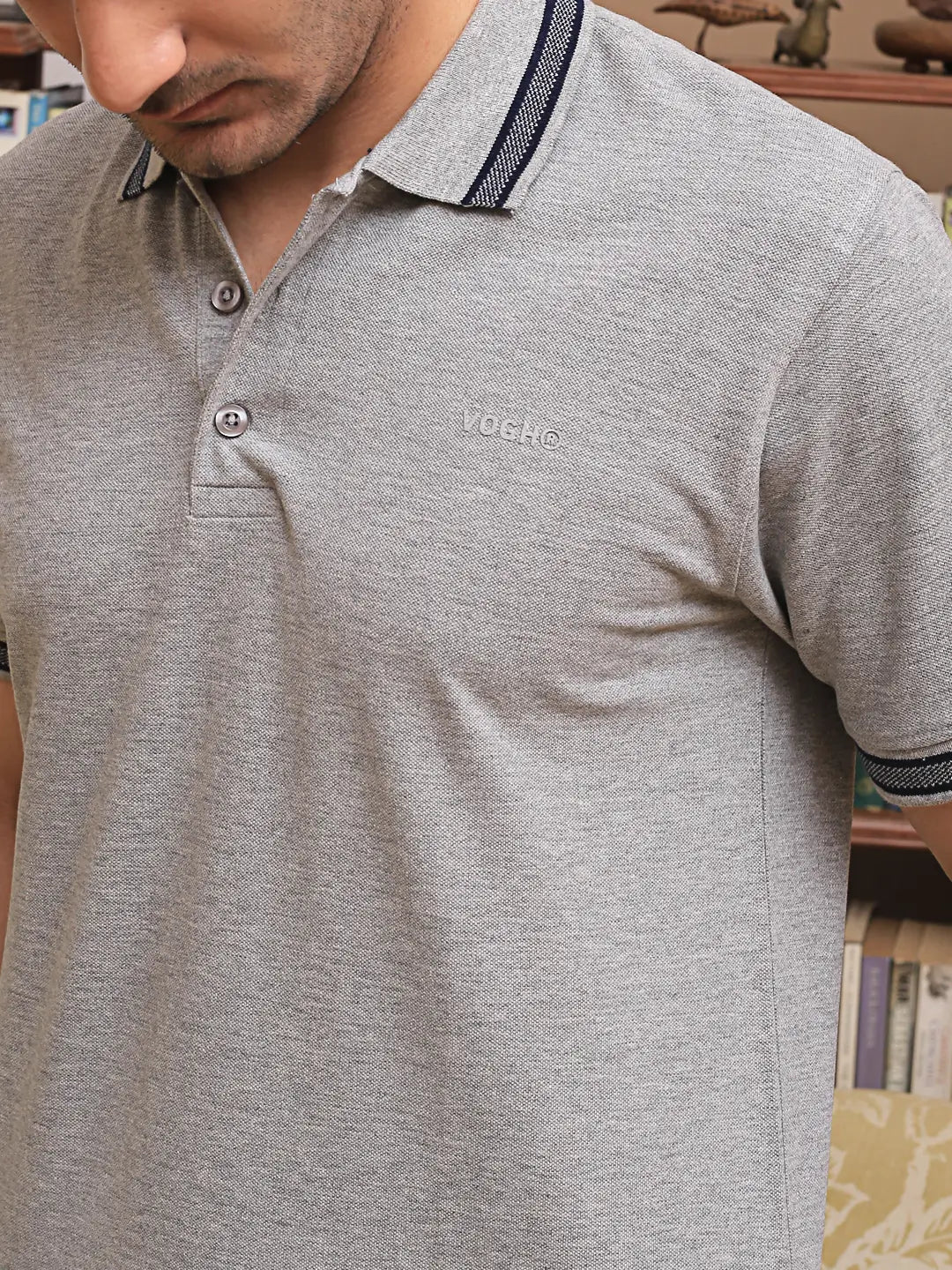 Gray cotton polo t shirt with a brand logo worn by a person, indoor setting