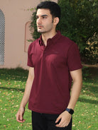 Man wearing a maroon polo shirt standing outdoors