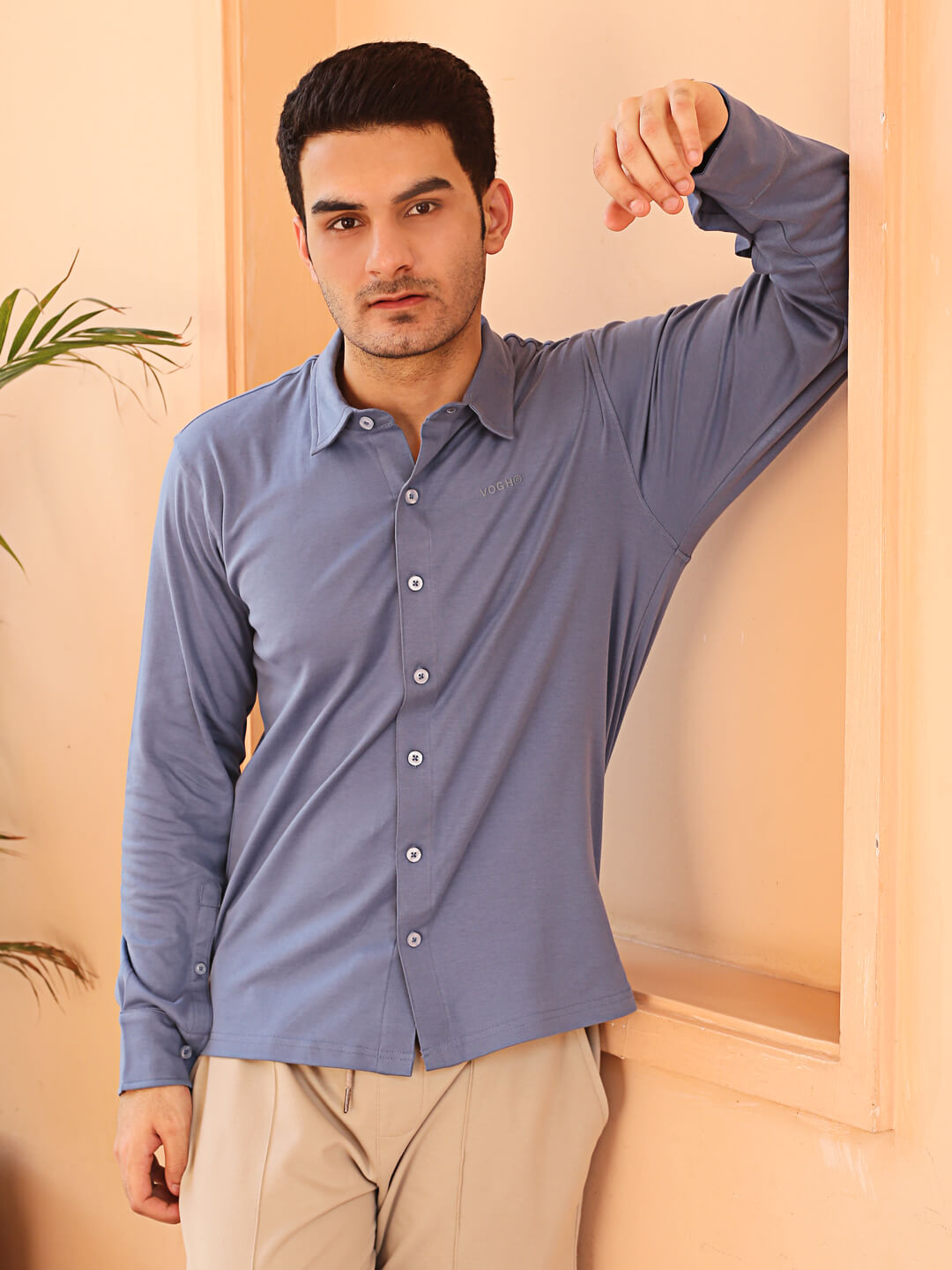 A man wearing a grey knit cotton shirt and beige pants