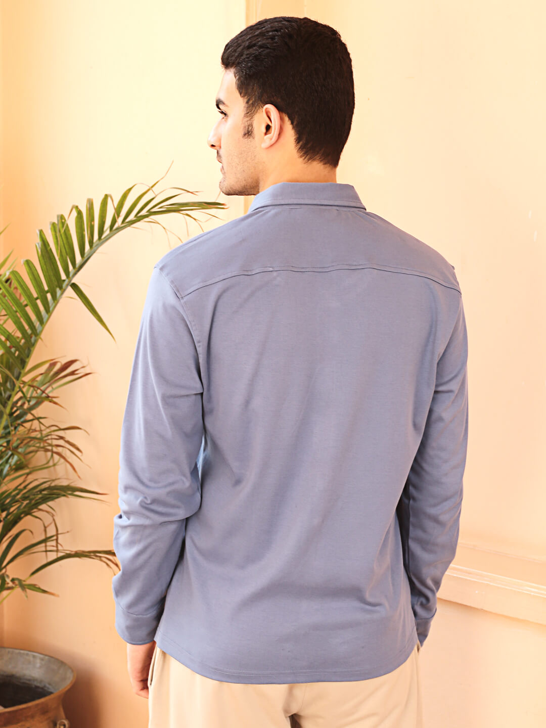 A man wearing a grey knit cotton shirt and beige pants