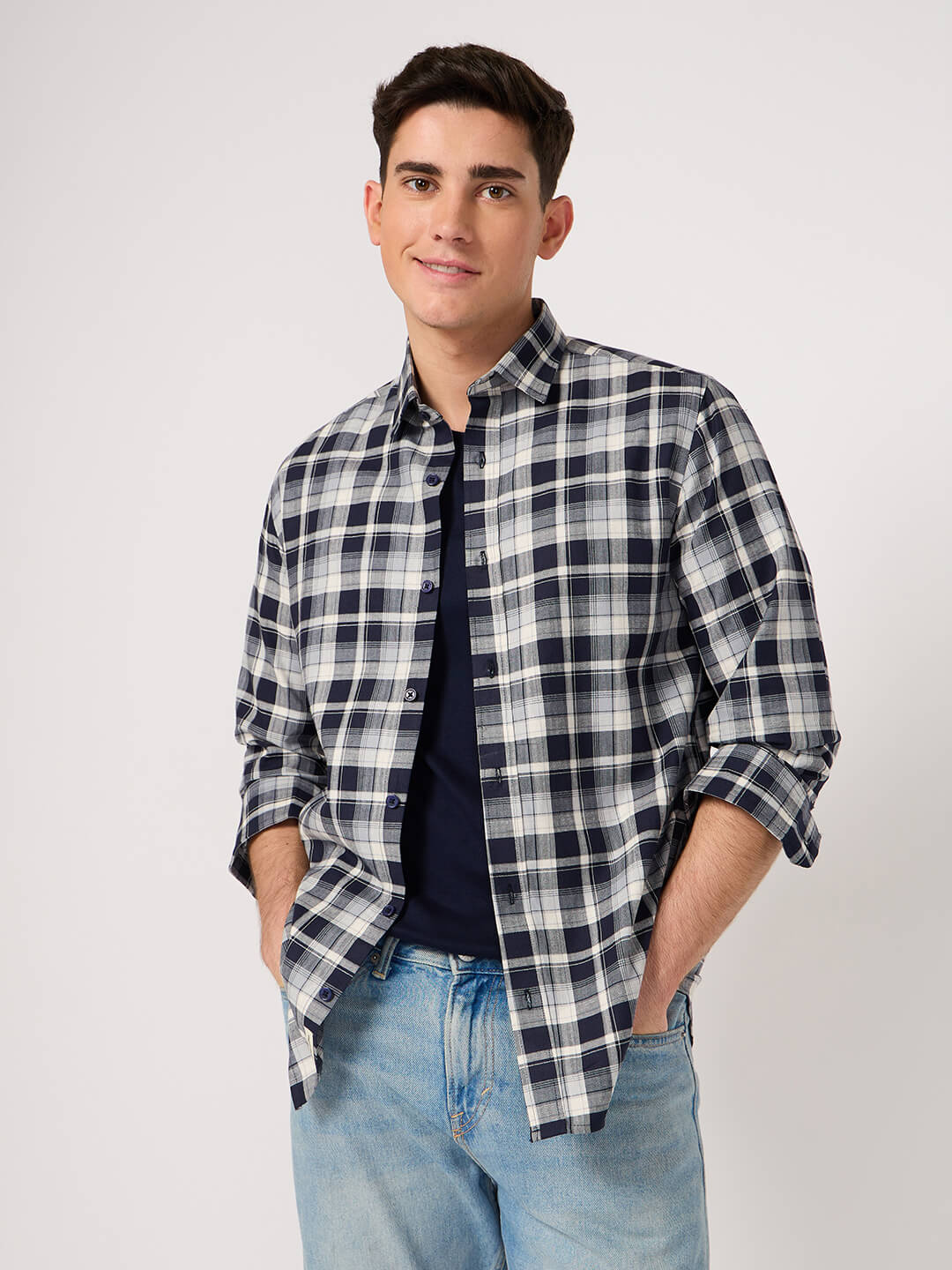 Man wearing a plaid shirt and jeans on a plain background