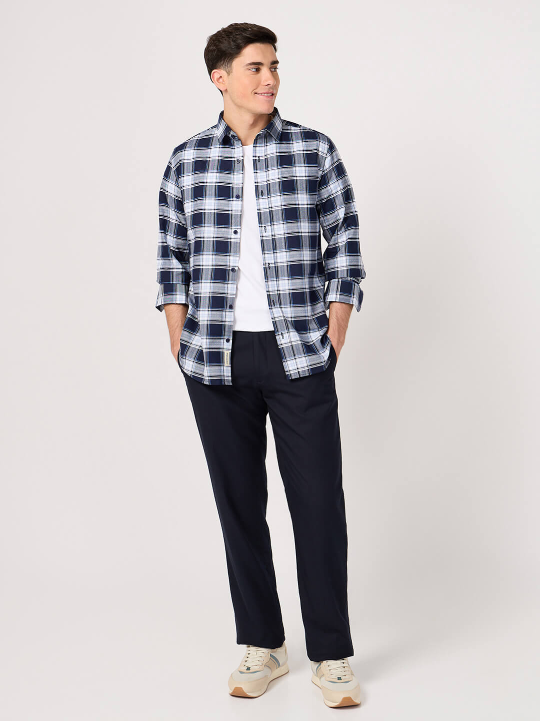 Man wearing a blue and white plaid shirt with dark pants on a white background