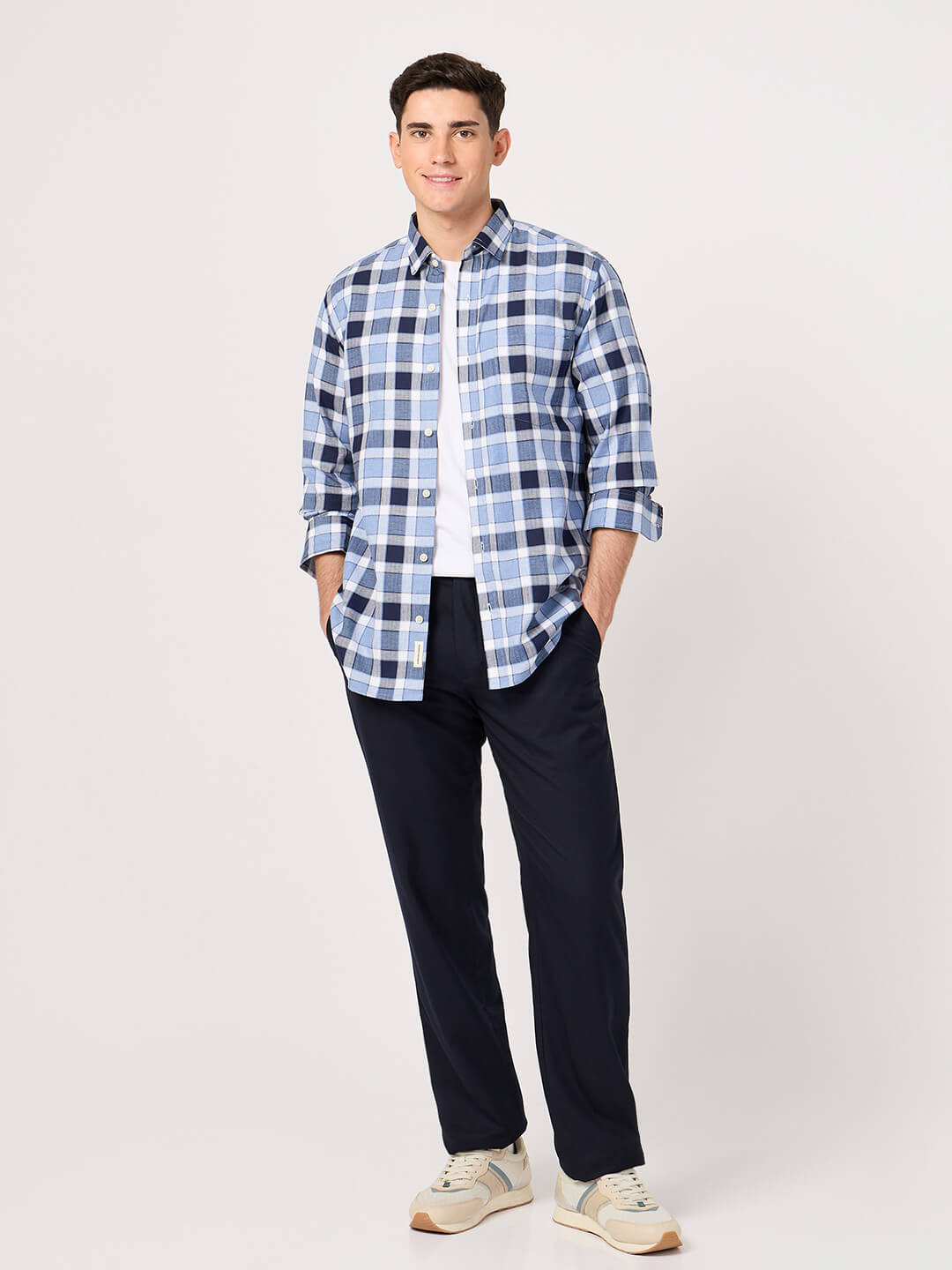 Man wearing a cotton blue check shirt and dark pants on a white background