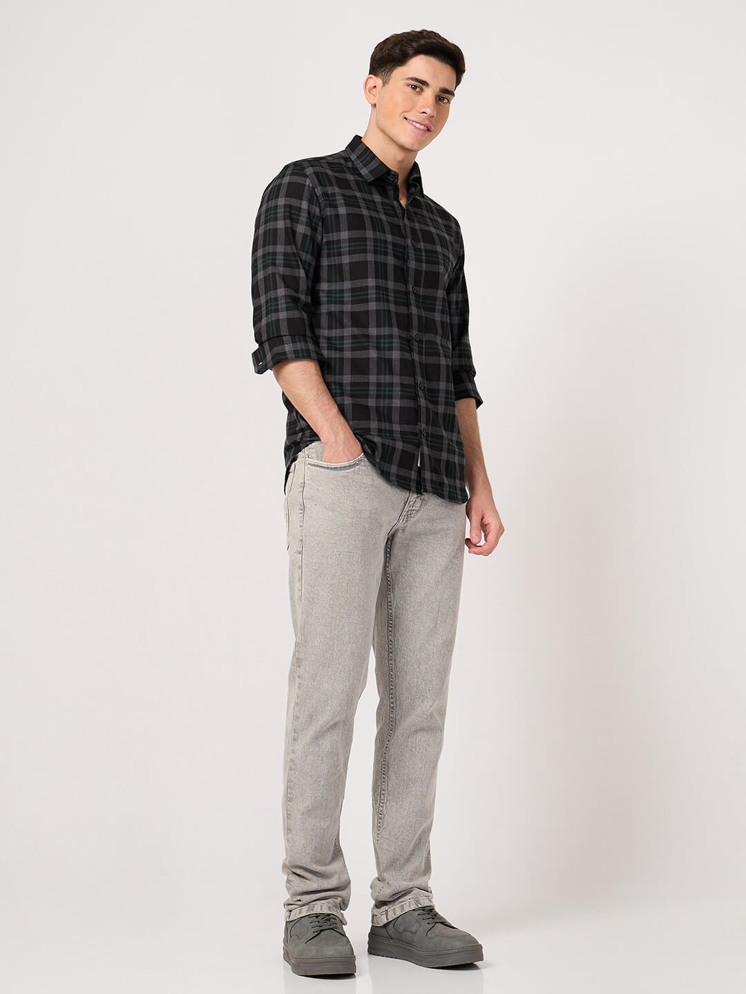 Man wearing a black and gray plaid shirt with gray pants on a white background