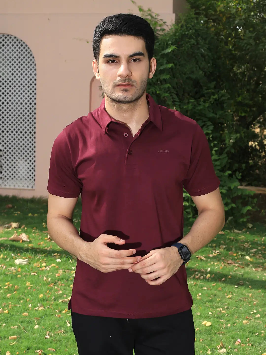 Man wearing a maroon polo t shirt standing outdoors
