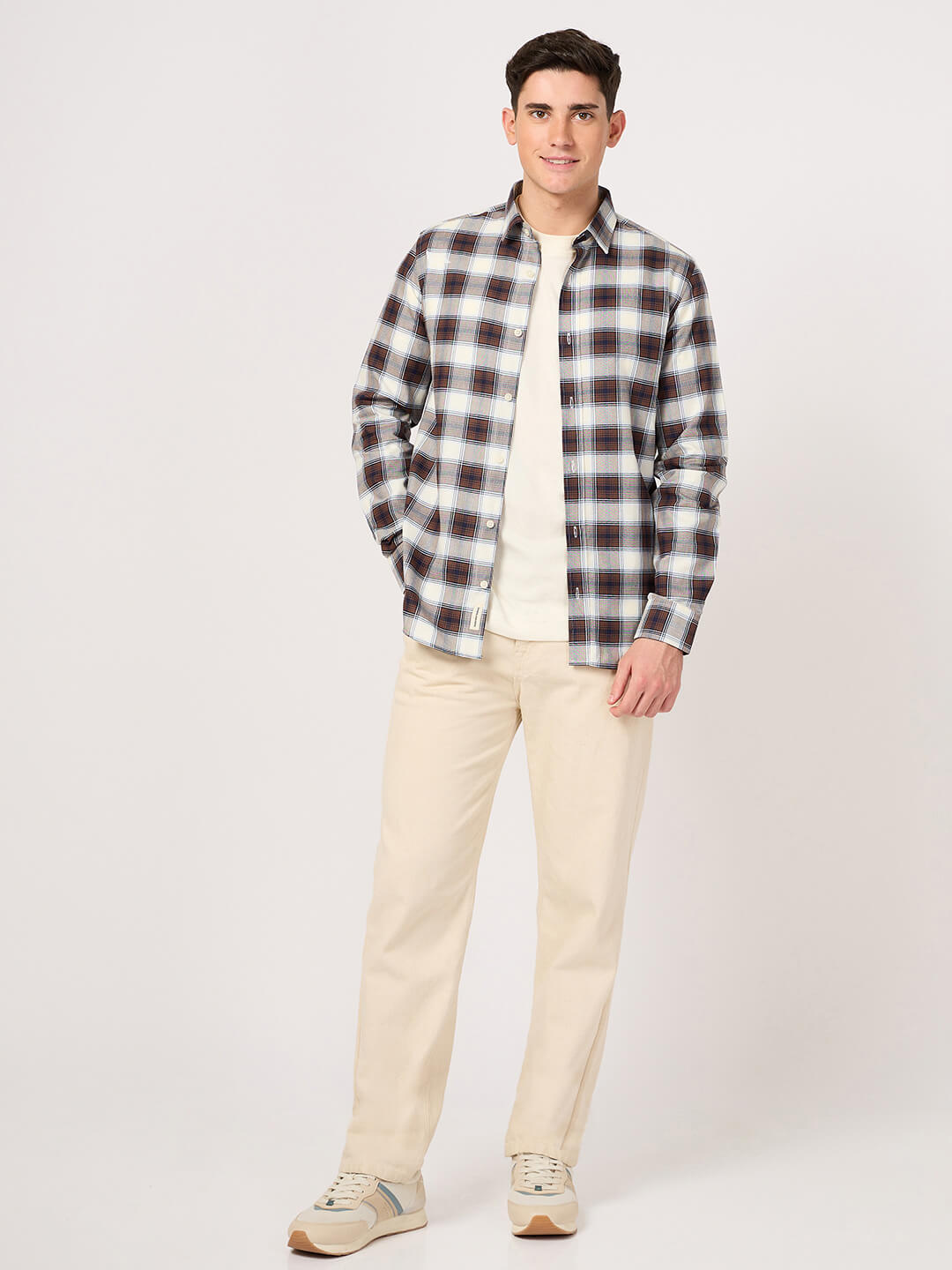 Man wearing a plaid shirt and beige pants on a white background
