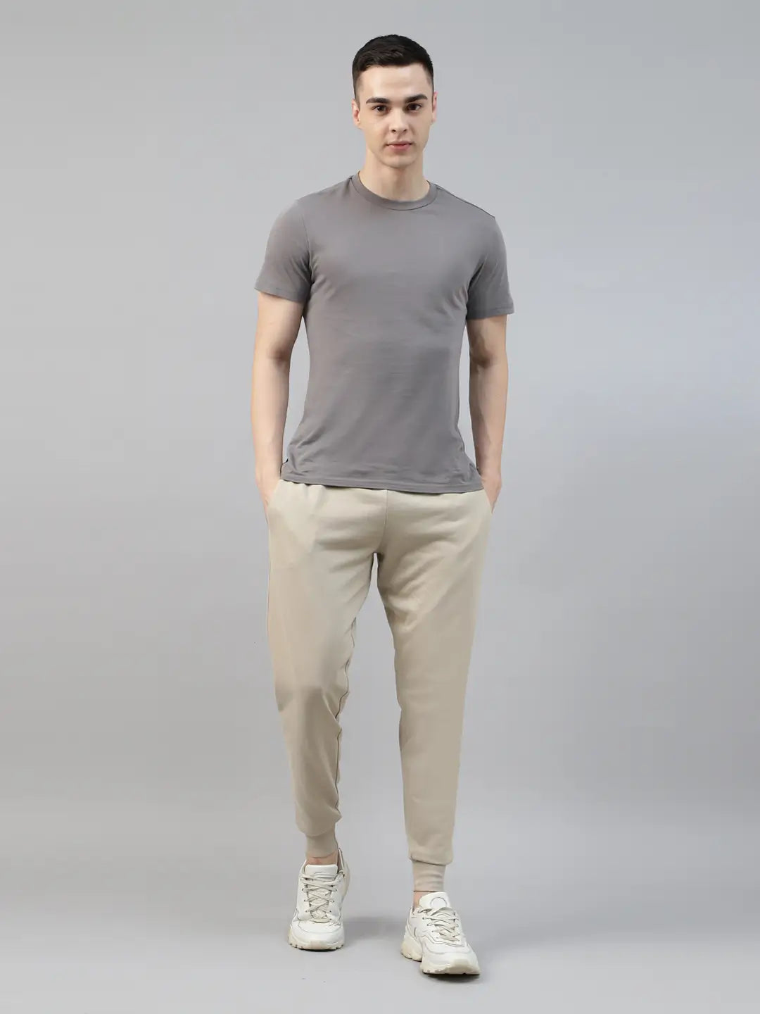 Man wearing a gray t-shirt and beige jogger pants on a gray background