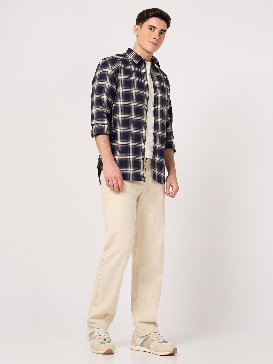 Man wearing a cotton check shirt and beige pants on a white background