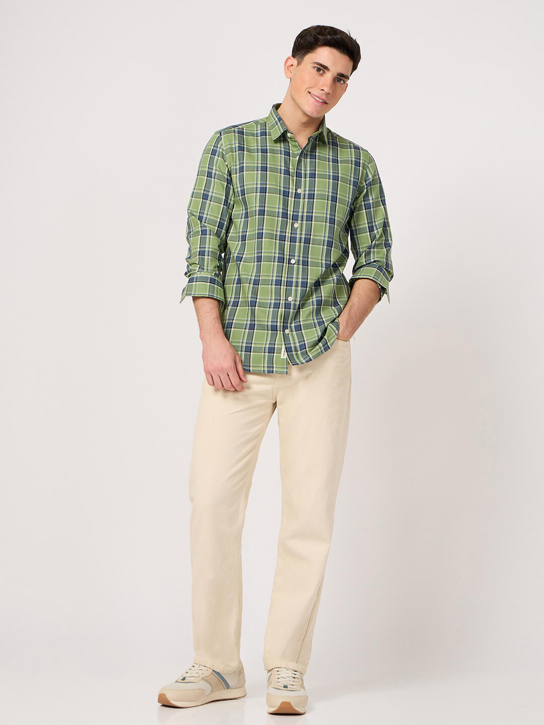 Man wearing a green plaid shirt and beige pants on a white background