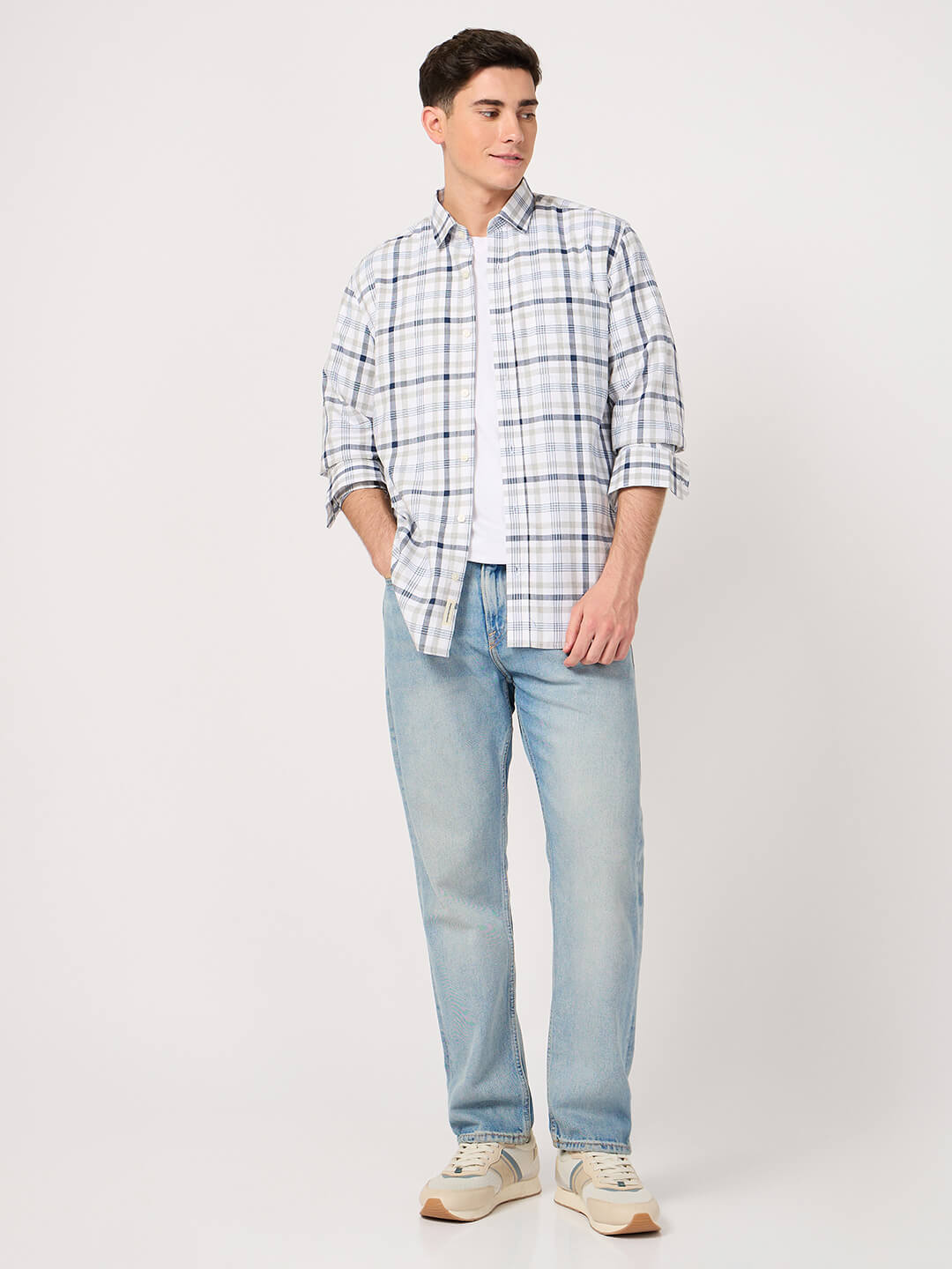 Man wearing a check cotton shirt and light blue jeans on a white background