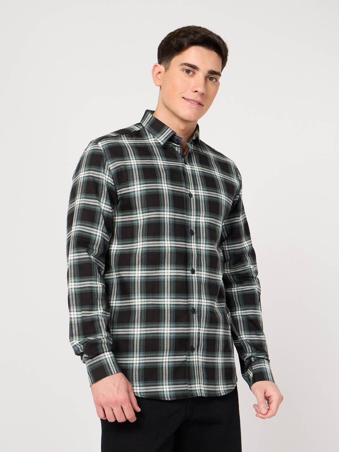 Man wearing a black and green plaid shirt on a white background
