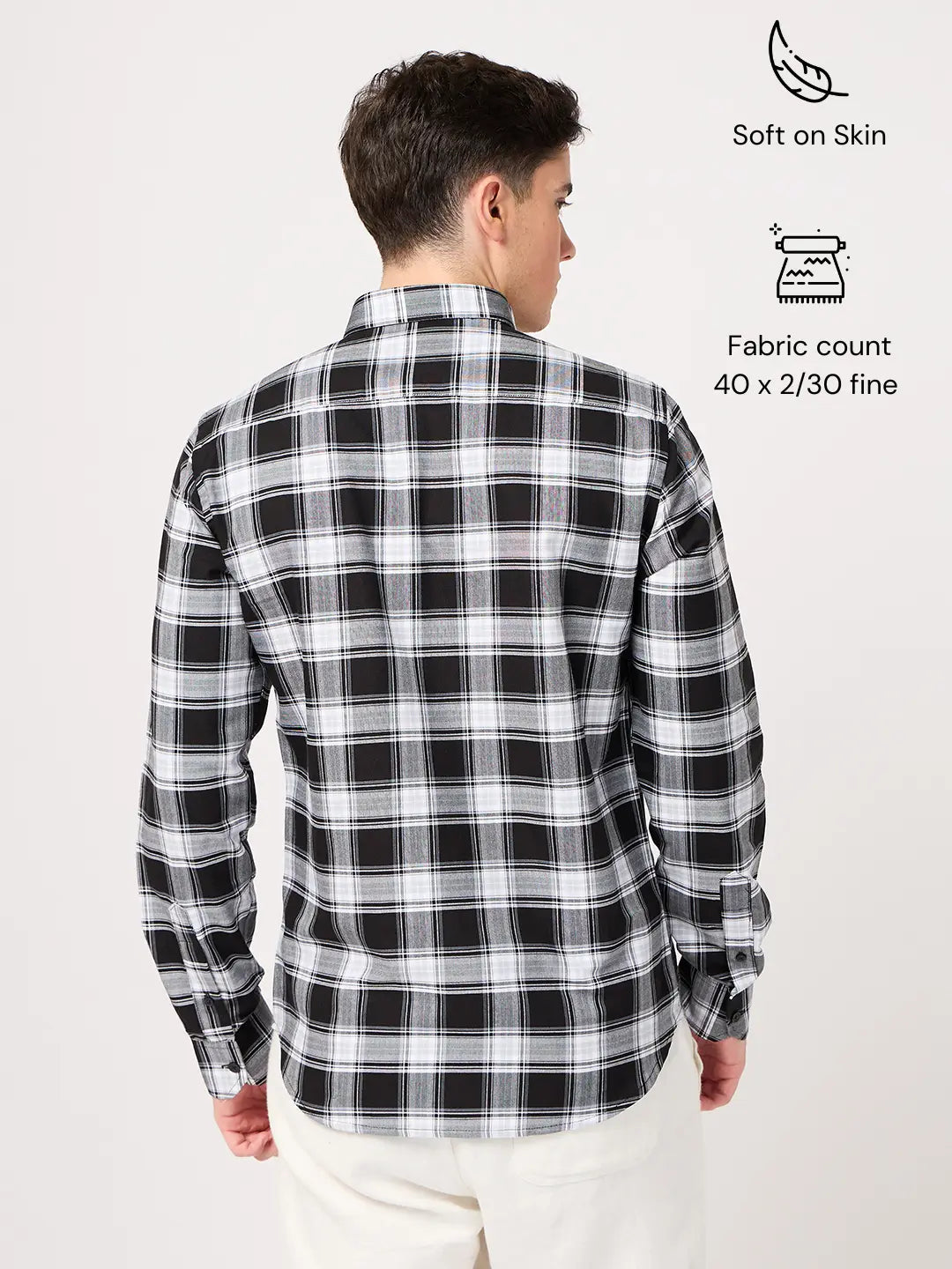 Person wearing a black and white checkered shirt with fabric details on a light gray background