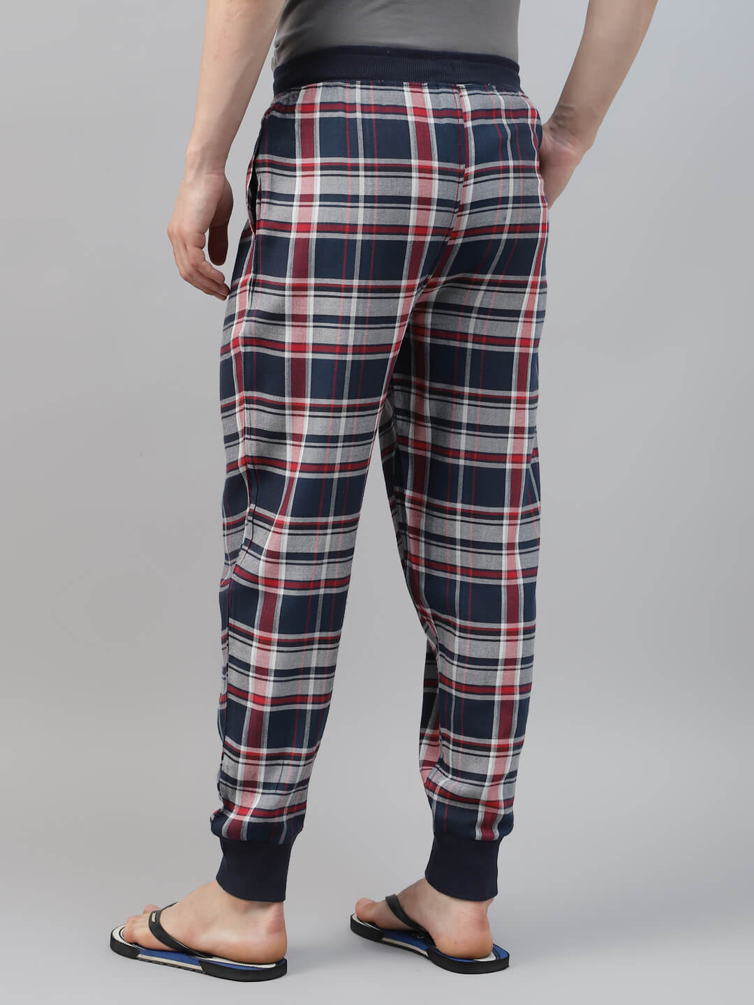 Plaid pajama pants worn by a person on a gray background
