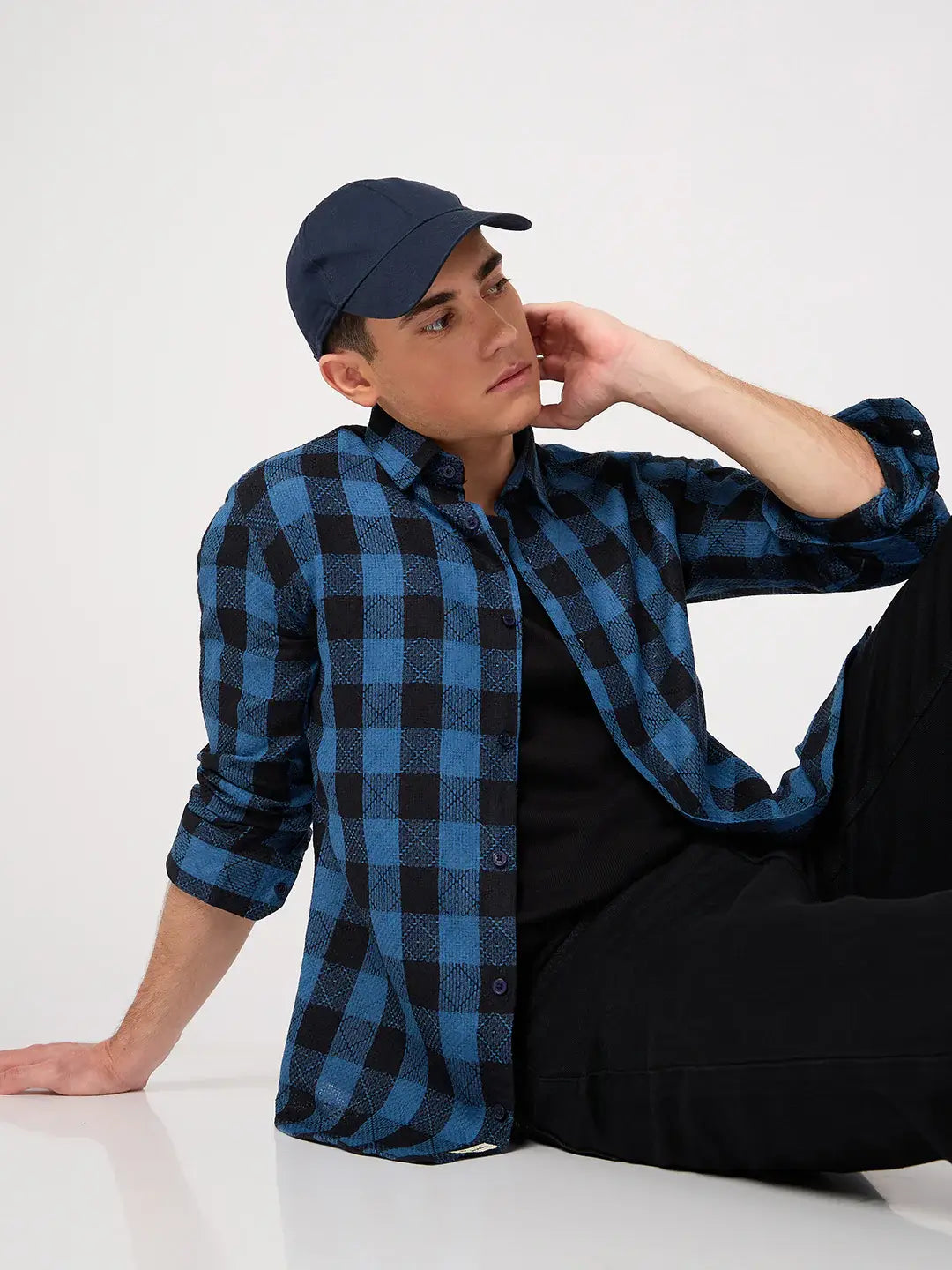 Person wearing a blue and black checkered shirt and cap