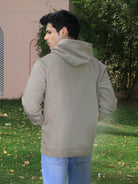 Person wearing a grey hoodie and blue jeans standing outdoors