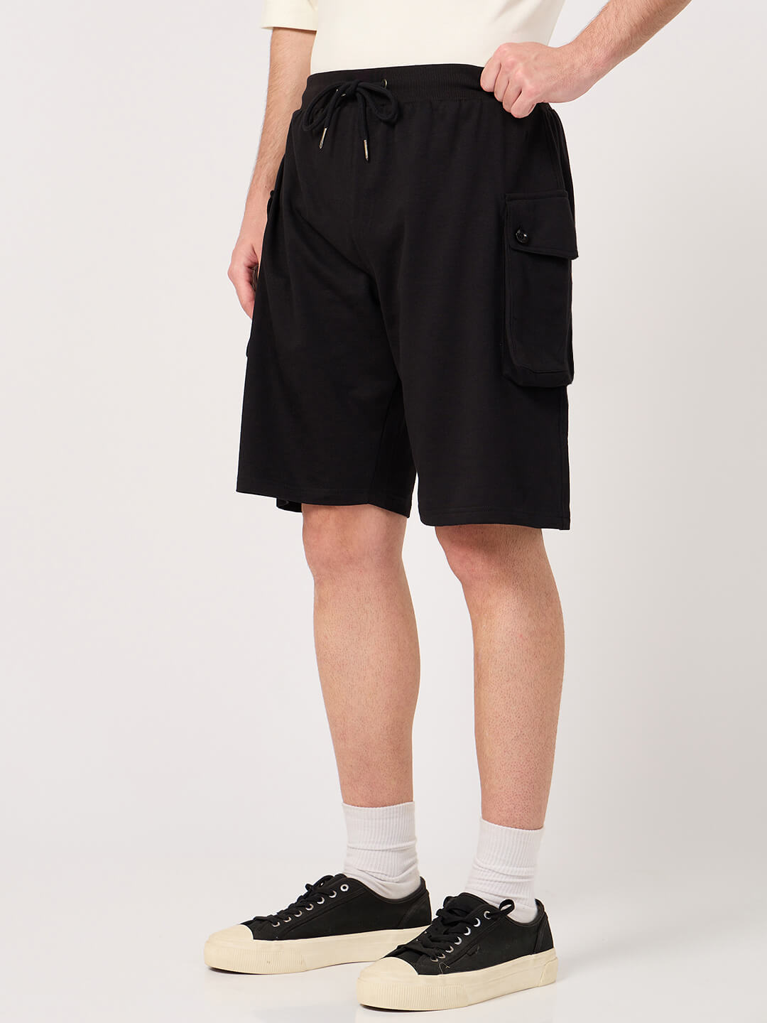Person wearing black cargo shorts on a white background