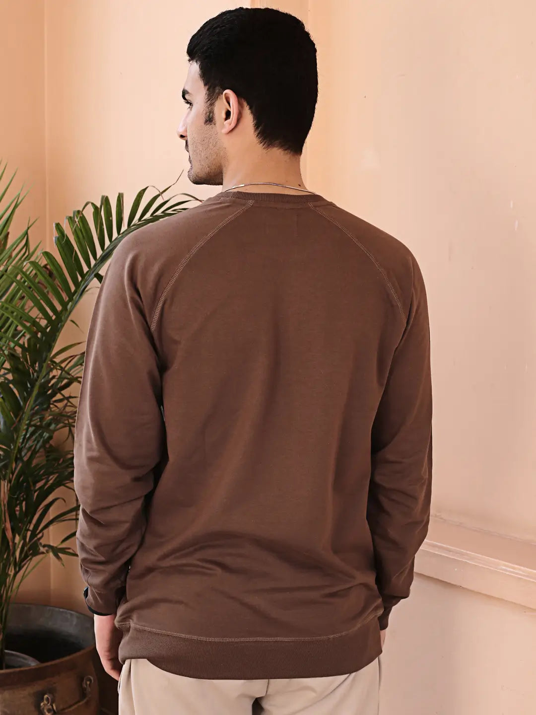 Man wearing a brown sweatshirt standing in a room