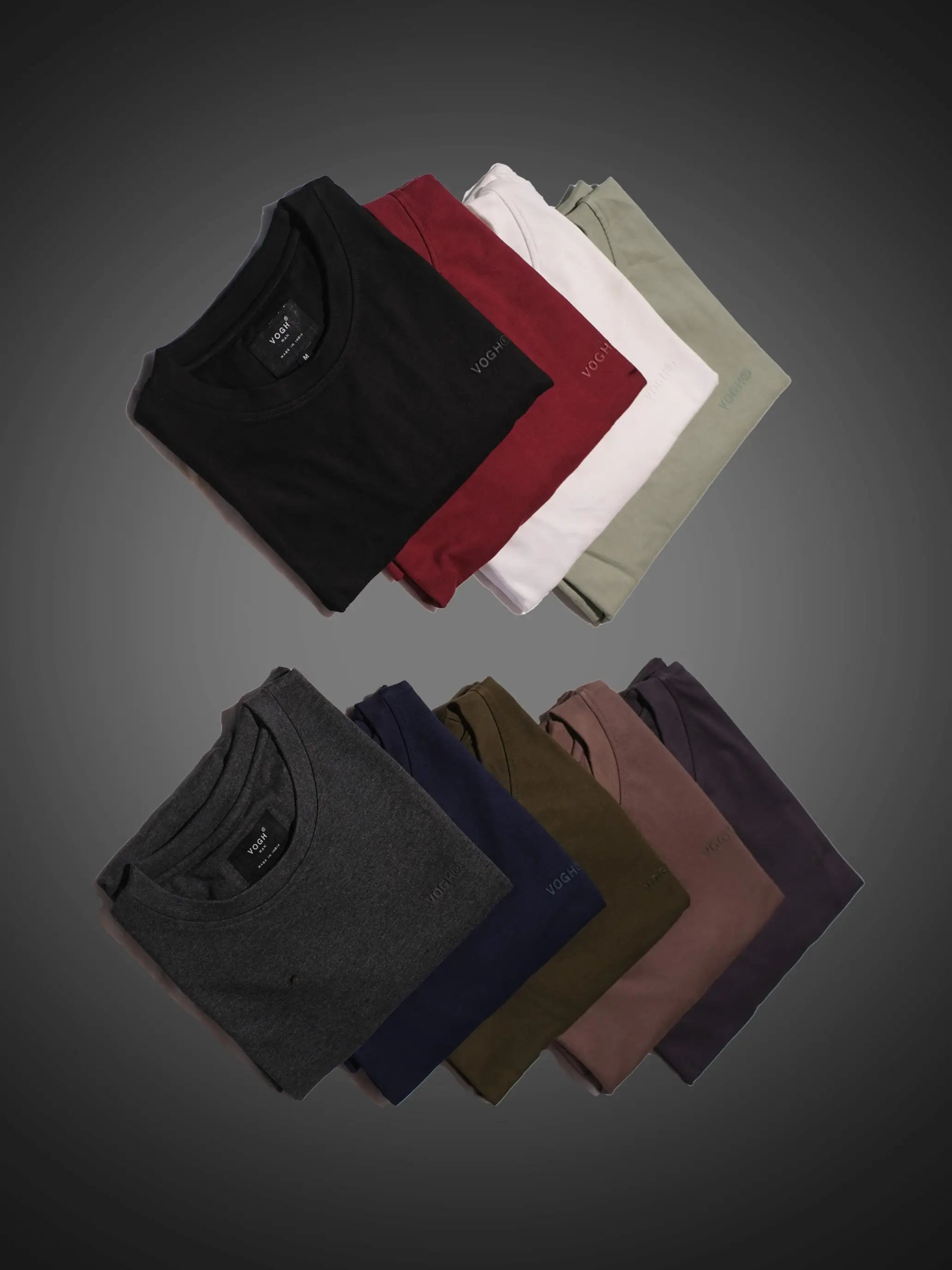 Folded t-shirts in various colors on a gray background