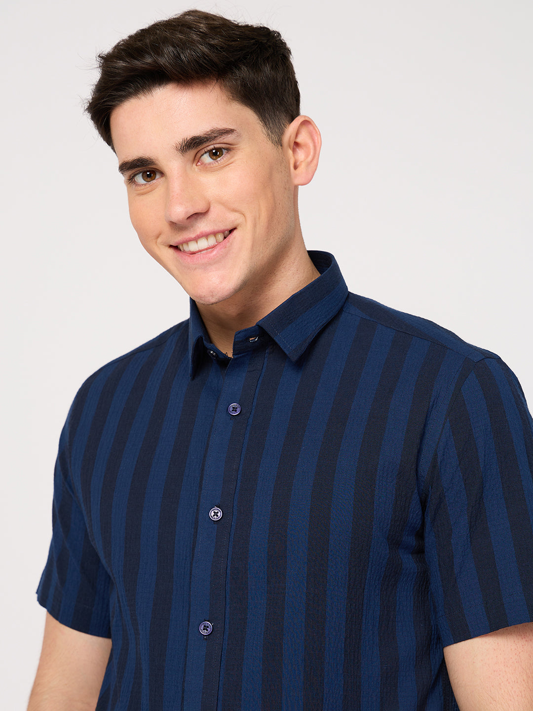 A man wearing a blue striped cotton half sleeve shirt with a collared neckline.