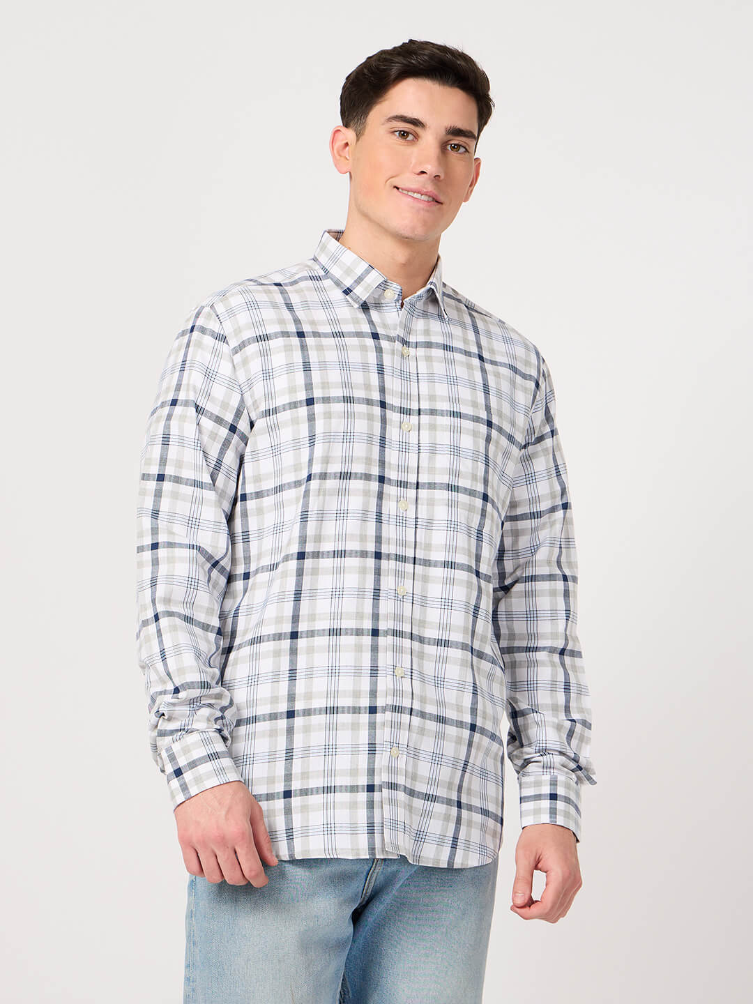 Man wearing a cotton check shirt and jeans on a white background