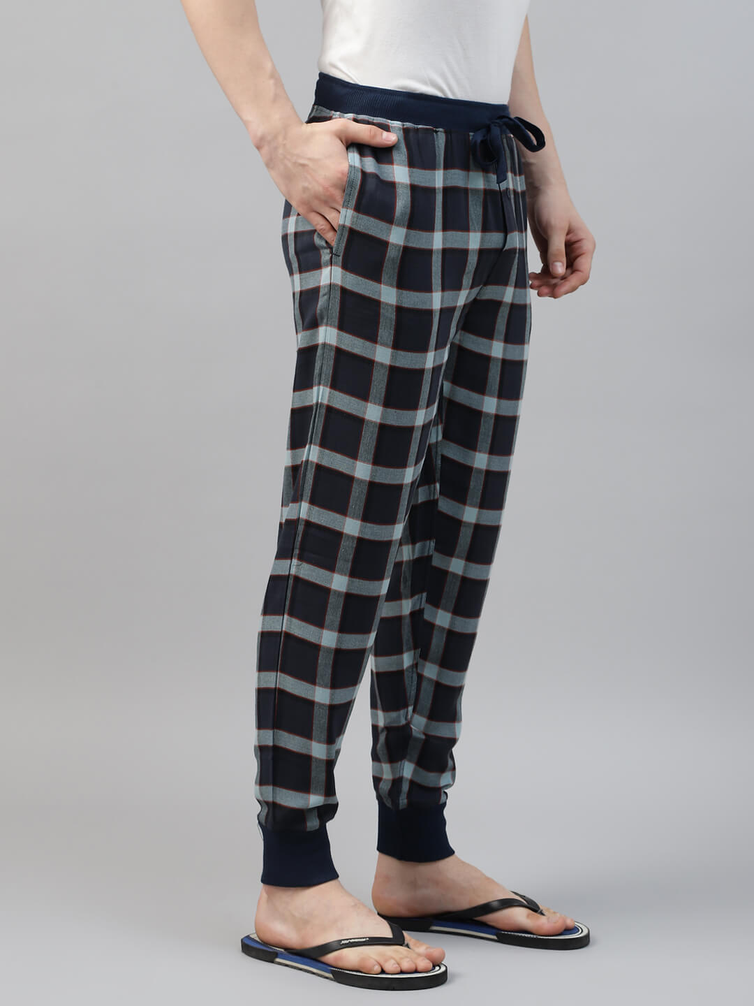 Person wearing black and white plaid jogger pants on a gray background