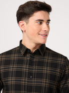 Man wearing a black and brown plaid shirt against a white background