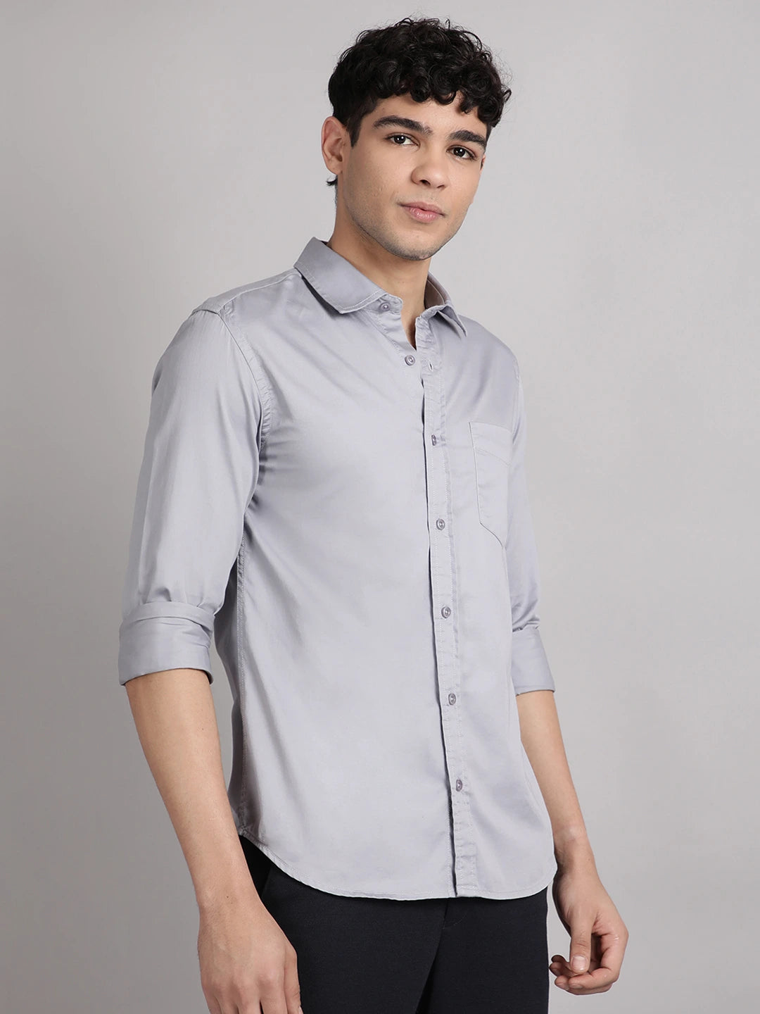 Man wearing a light gray shirt with rolled-up sleeves