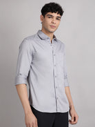 Man wearing a light gray shirt with rolled-up sleeves