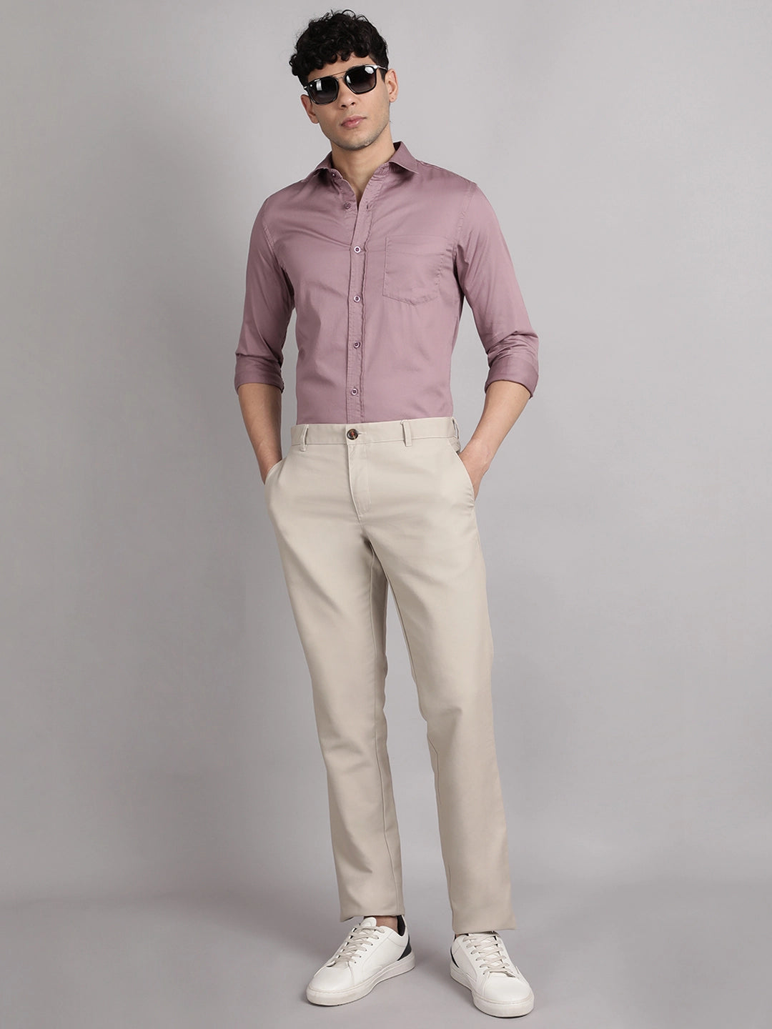 Man wearing a shirt, beige pants, and white sneakers on a gray background