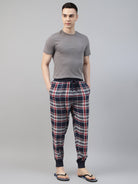 Man wearing a gray t-shirt and plaid jogger pant on a gray background
