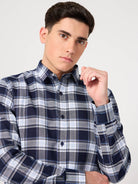 Man wearing a blue and white plaid shirt against a plain background