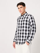 A man wearing a black and white checked shirt with full sleeves and white trouser