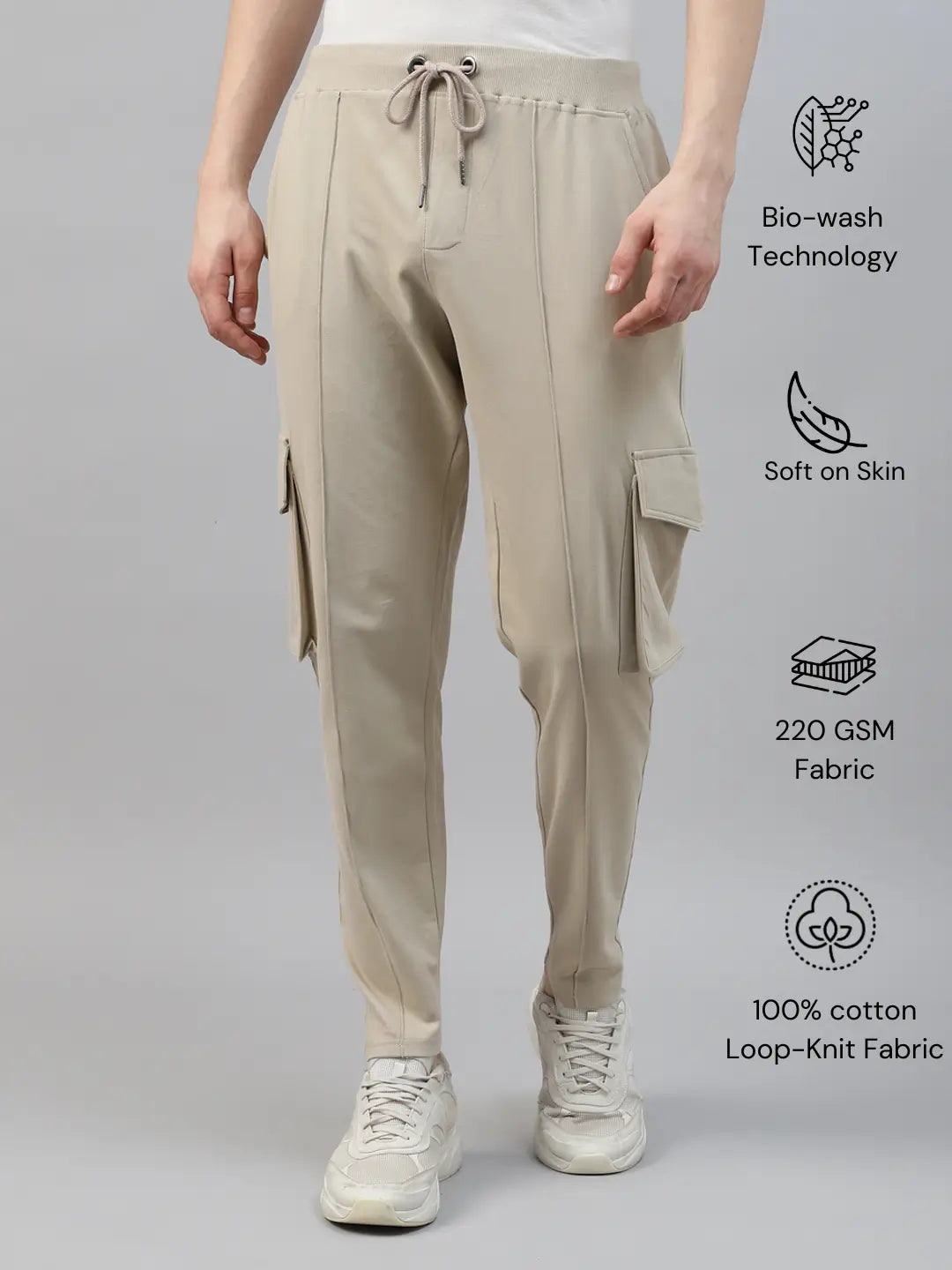 Beige cotton cargo pants worn by a person on a gray background