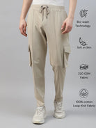 Beige cotton cargo pants worn by a person on a gray background